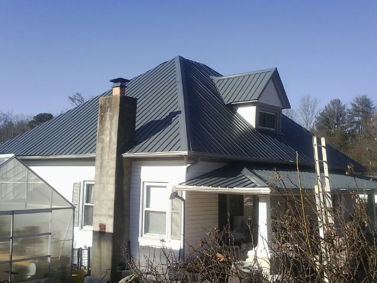 Dark blue standing seam metal roof on a white farmhouse with dormer — Slate & Tile Roof Repair by Roofing Brothers in Scituate