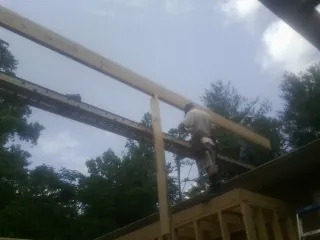 Carpenter setting a ridge beam over a new addition frame — Ice Dam Removal by Roofing Brothers in Scituate