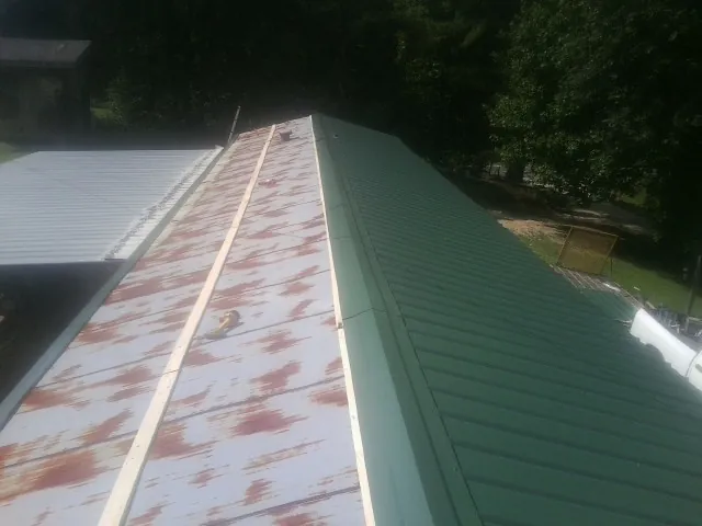 Old rusted panels beside newly installed green metal roofing — Wind Damage Roof Repair by Roofing Brothers in Scituate