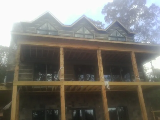 Dormers and porch framing on a large log home under construction — Roof Coating work by our crew in Scituate