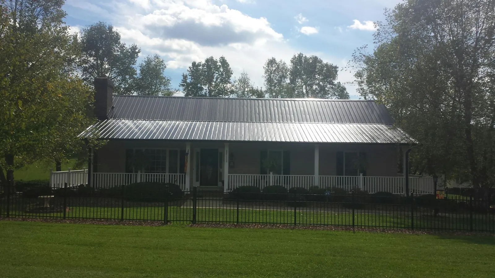 Gray metal roof on a brick ranch with a full width front porch — Gutter Guard Installation work by our crew in Scituate
